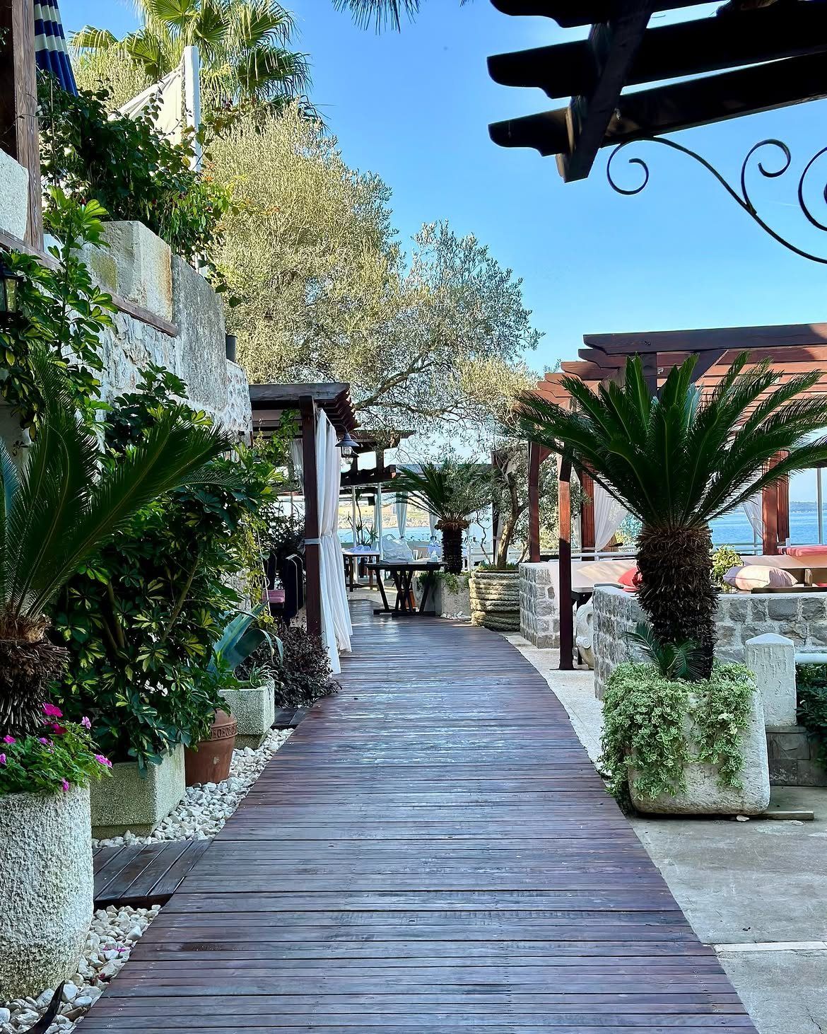 Drveno šetalište kroz bašte Ribarskog Sela na Luštici, palme i more na kraju staze